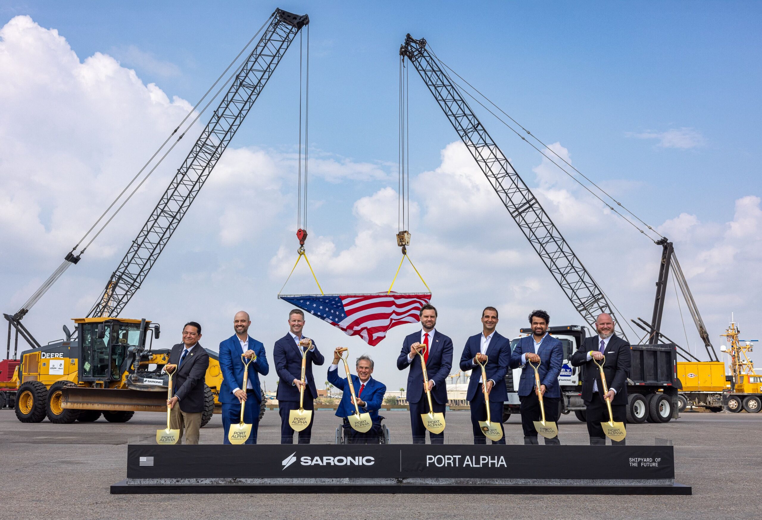 Participants holding ceremonial shovels at Saronic’s Port Alpha groundbreaking, with cranes and Port Alpha signage behind them.